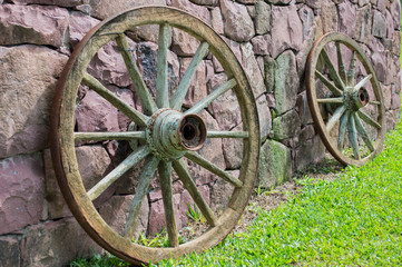 Fototapeta na wymiar wagon wheels on purple stone wall