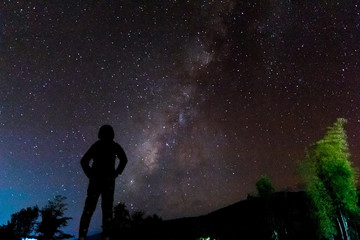 Fototapeta na wymiar Silhouette of a standing human looking milky way at the night time