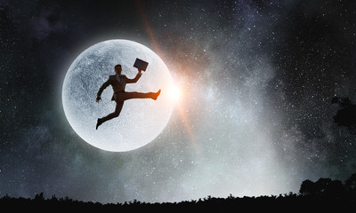 Obraz na płótnie Canvas Silhouette of businessman over moon . Mixed media