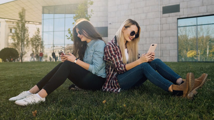 Two attractive hipster girls using smart phone. 