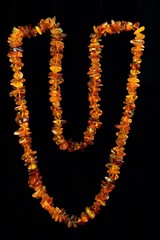 Amber beads on a black background, the beautiful petrified fossil resin of ancient coniferous trees. Used for the manufacture of jewelry and haberdashery. 