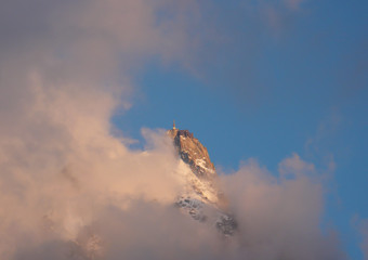 clouds and fog hide the famous Aiguille du Midi station at sunrise in the French Alps
