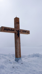 wooden summit cross on the Alphubel mountain peak covered in deep snow in winter