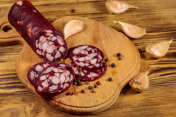 Sliced salami sausage on cutting board on wooden table