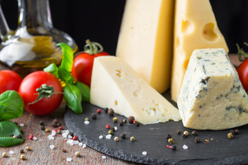 Different kind of cheese, tomato and basil on a wooden table. Vegetarian food