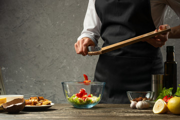 Freezing food prepares a vegetarian salad with seafood by the chef in the home kitchen. A concrete wall background with a text area for restaurant menu design.