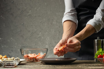 The chef handles shrimps in the domestic kitchen. Backgrounds from the concrete wall with a text area for restaurant menu design