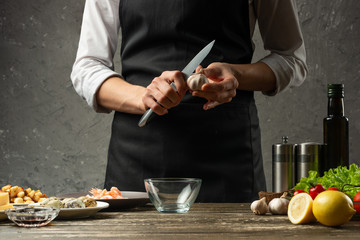 Chef with garlic at home kitchen. Background from a concrete wall with a text area for restaurant menu design