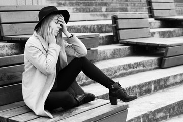 Teenager girl with depression sitting on the stairs. Black and white photo