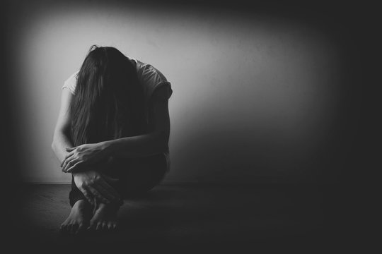 Teenager Girl With Depression Sitting Alone On The Floor In The Dark Room. Black And White Photo