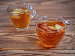 Tea with apples in glass mugs on wooden background