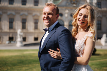 Couple in wedding dress stand near the palace and have fun