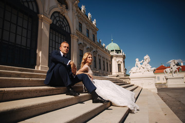 Fashion photo of wedding couple. Groom wears blue suit and tie bow. Bride wears white wedding dress