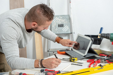 young man using a tablet to tinker at home