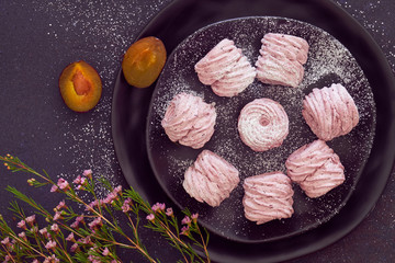 Flat lay with a plate of home-made marshmallows (zephyr, meringue) made with black plums