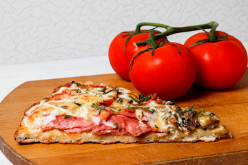 Italian rustic pizza, one piece on a wooden tray, white wooden table, with tomatoes and cheese