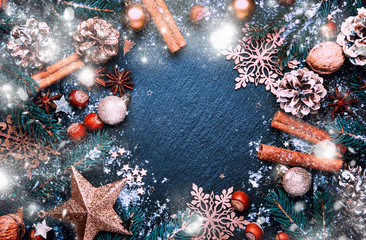 Obraz na płótnie Canvas Christmas or New Year dark background, frame, template, with festive decorations, winter spices and Christmas decorations, nuts and fir branches, top view