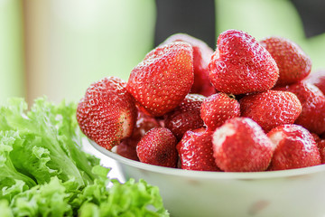 Fresh juicy large strawberry in a bowl close-up outdoors at the cottage