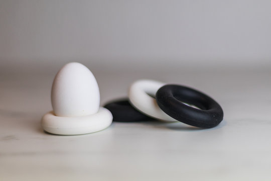 Four Black And White Silicon Eggcups On A Marble Table With Only One Egg