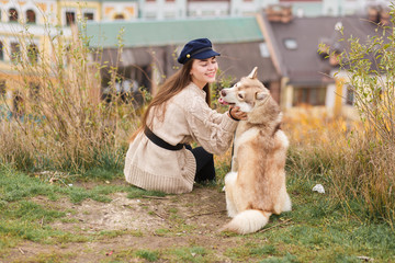 young woman with her husky dog in old city sitting on high hills. Human and animal friendship concept