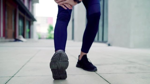 Slow motion - Healthy beautiful young Asian Athlete women sports clothing legs warming and stretching her arms to ready for running on street in urban city. Lifestyle active exercise in city concept.