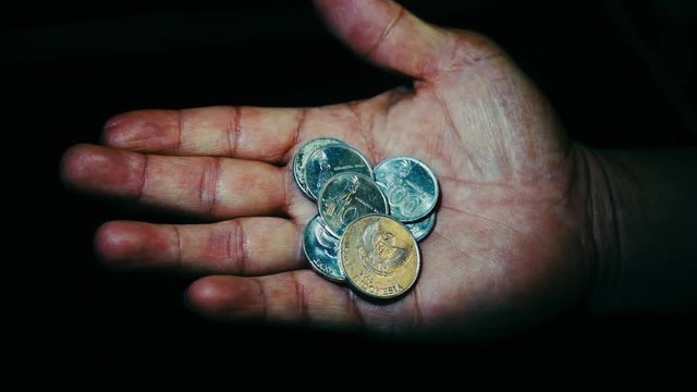 Indonesia rupiah coins in the hand of an asian person isolated. Concept of small salary not enough for the living