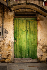 Old and rustic green wooden door. Exterior door in a house of the middle evo.