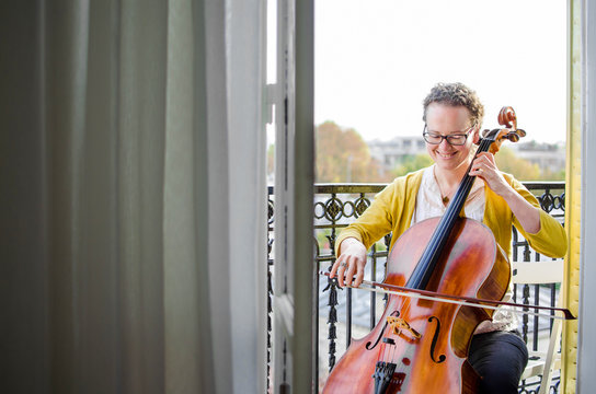 Female classical musician playing cello on the balcony in France