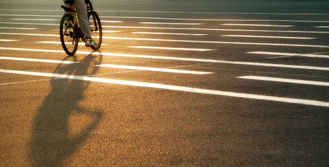 Cyclist riding along a road lined with lines in the rays of the setting evening sun