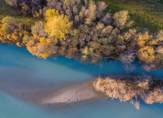 Aerial view of river in evening sunlight in Switzerland with sandbank and yellow trees