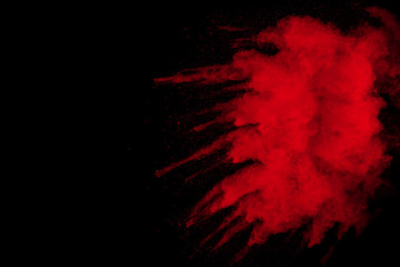 Red powder explosion on black background. Freeze motion of red dust particles splash on dark background.