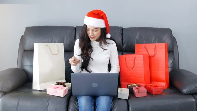 woman in santa hat shopping online for Christmas gift with laptop in the living room