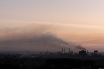 Fototapeta na wymiar Large pipes of the plant pollute emissions environment at sunset
