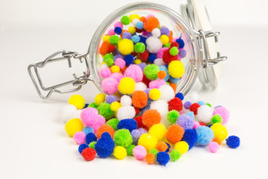 brightly colored pom-poms in a glass jar