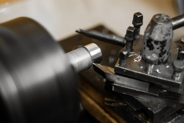 turning a rotating workpiece on a old manual metalworking lathe, focus on the tip of the tool bit