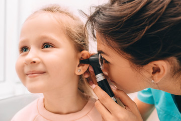 Pediatrician examining little patient with otoscope, hearing exam of child