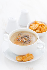 delicious mushroom cream soup with croutons on white table, vertical