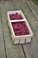 Basket with organic raspberries on vintage wooden background.