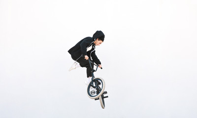BMX rider makes a TAilwhip trick on a white background. Young man doing tricks in the air on a BMX bike. BMX freestyle