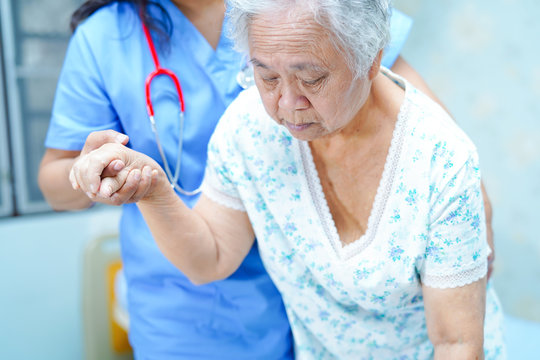 Asian Nurse Physiotherapist Doctor Care, Help And Support Senior Or Elderly Old Lady Woman Patient Get Up From Bed At Hospital Ward : Healthy Strong Medical Concept.