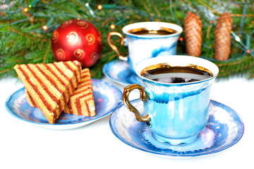 Pair vintage elegant stylish graceful beautiful porcelain cup with golden handle of morning tea or coffee on background of saucer with biscuit, fir branches with red Christmas ball and cone