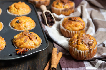 Fresh homemade apple cinnamon muffins in black baking dish on rustic wooden table.