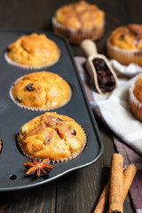 Fresh homemade apple cinnamon muffins in black baking dish on rustic wooden table.