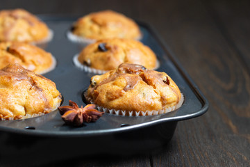Fresh homemade apple cinnamon muffins in black baking dish on rustic wooden table.