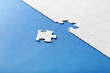 On a blue background, white puzzles and the missing piece
