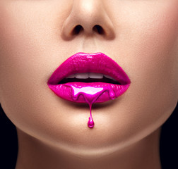 Roze lippenstift druipen. Lipgloss druipt van sexy lippen, paarse vloeistofdruppels op de mond van een mooi modelmeisje, creatieve abstracte make-up