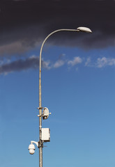 Surveillance system with an orange warning light located on a pole in the open. The threat of...