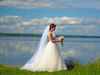 Fototapeta na wymiar Wedding. Bride with wedding bouquet on the background of a picturesque river