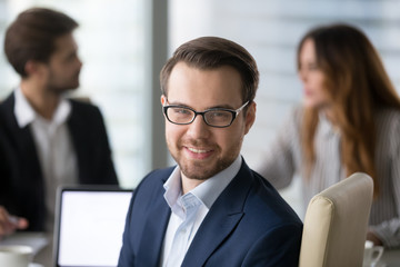 Head shot portrait of confident businessman or business owner at workplace, smiling man sitting at...