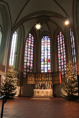 Fototapeta na wymiar Luneburg, Germany - 10.12.2017: Christmas altar in the catholic church and stained glass behind it